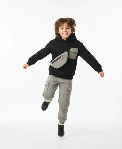 Child wearing a black hoodie with a gray pouch and gray pants on a white background