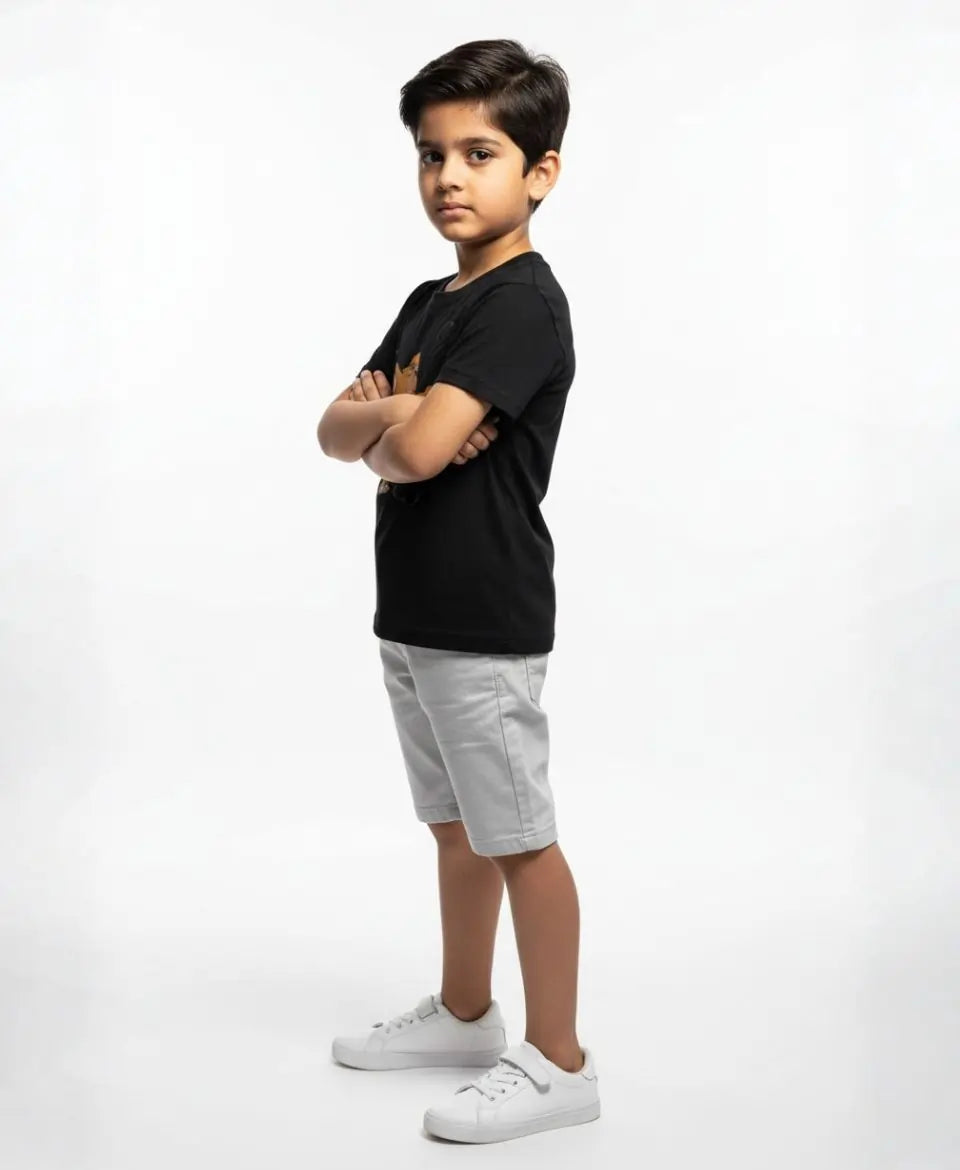 Child wearing a black t-shirt, gray shorts, and white sneakers on a white background