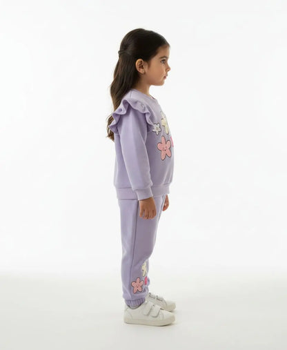 Child wearing a lavender tracksuit with floral designs on a white background