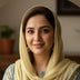 Woman wearing a light-colored headscarf with a blurred indoor background