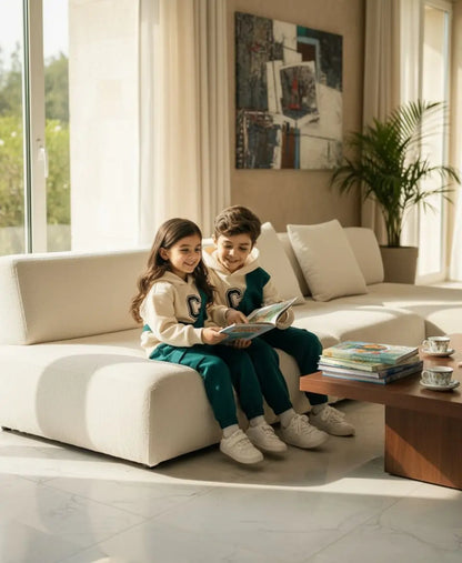 Two children sitting on a white couch in a modern living room, reading a book.