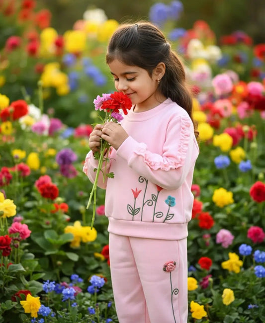 Young girl in a pink outfit holding flowers in a field of colorful flowers