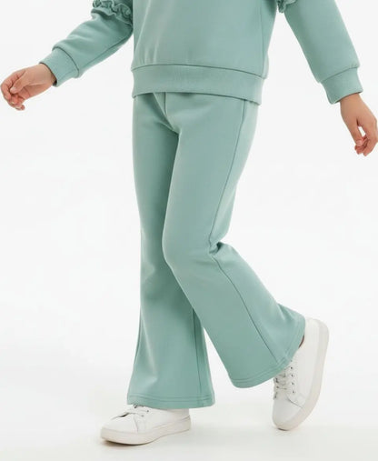 Person wearing a light green tracksuit with white sneakers on a white background