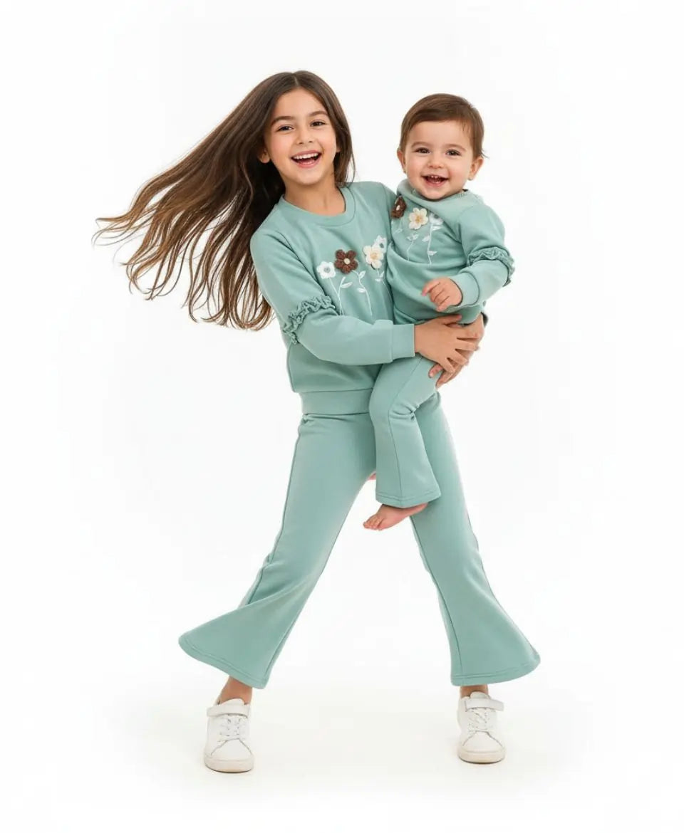 Two children in matching teal outfits on a white background