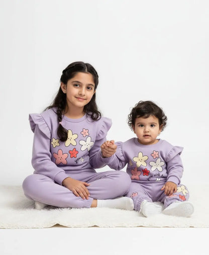 Two children wearing matching lavender pajamas with floral designs on a white background