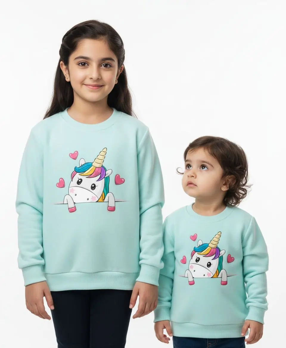 Two children wearing matching light blue sweatshirts with a unicorn design on a white background