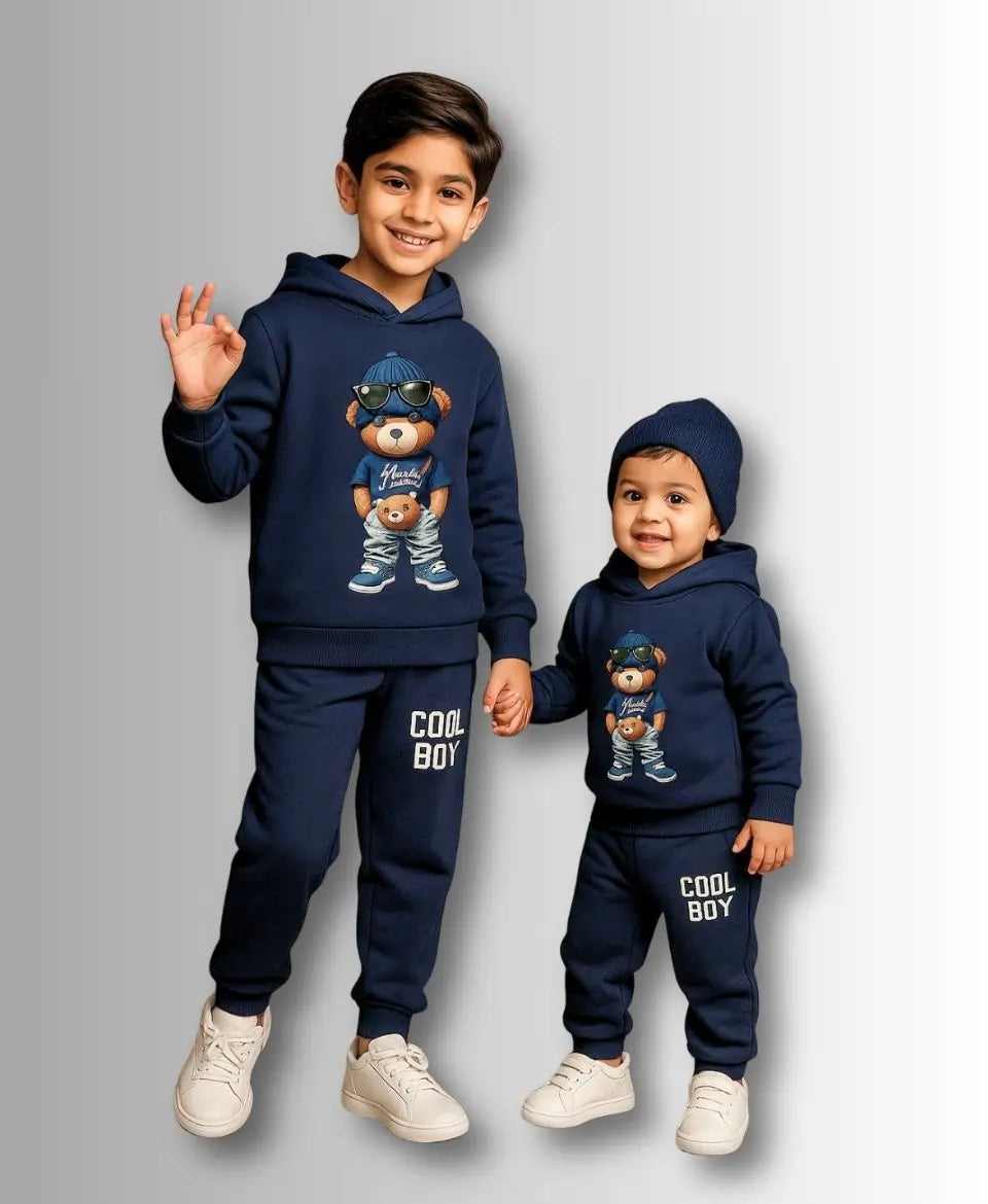 Two children wearing matching navy blue outfits with teddy bear graphics on a gray background