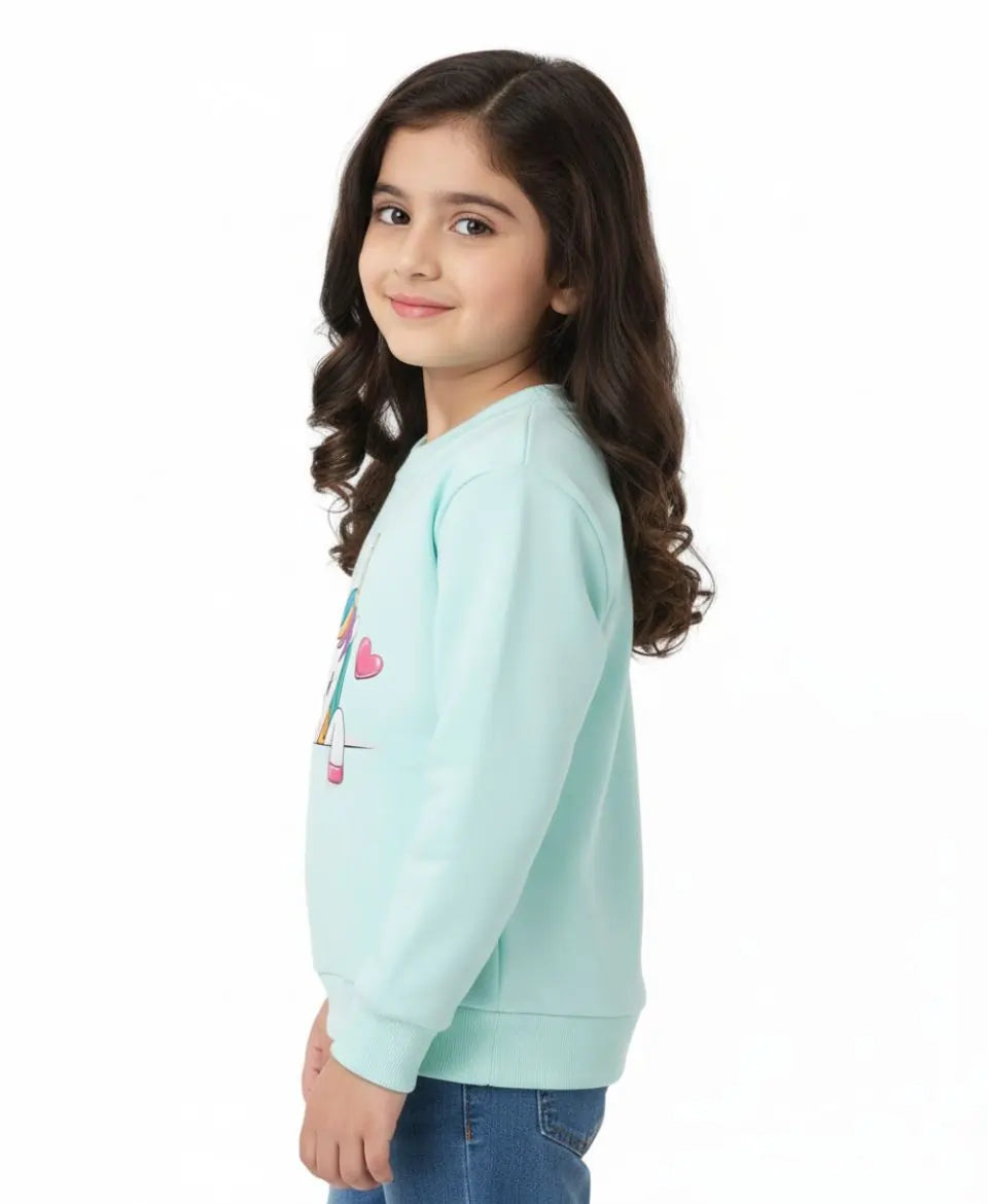 Young girl wearing a light blue sweatshirt with a design on a white background