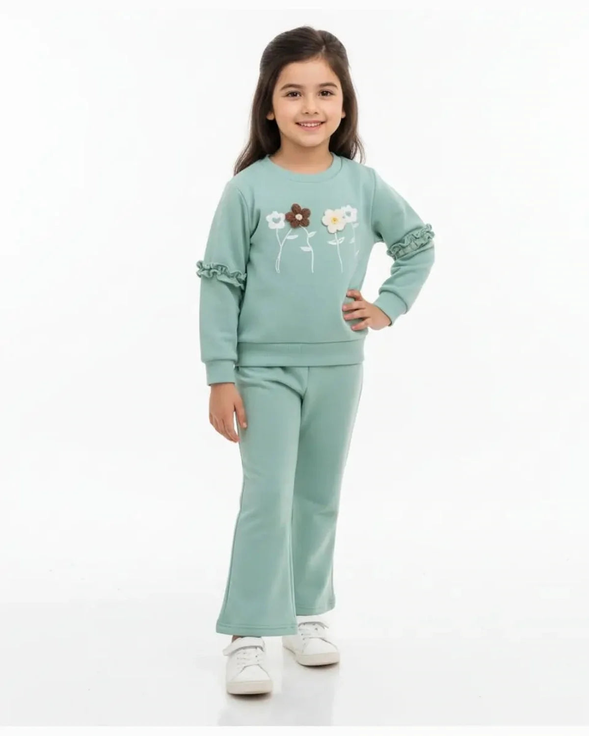 Young girl wearing a light green outfit with floral designs on a white background