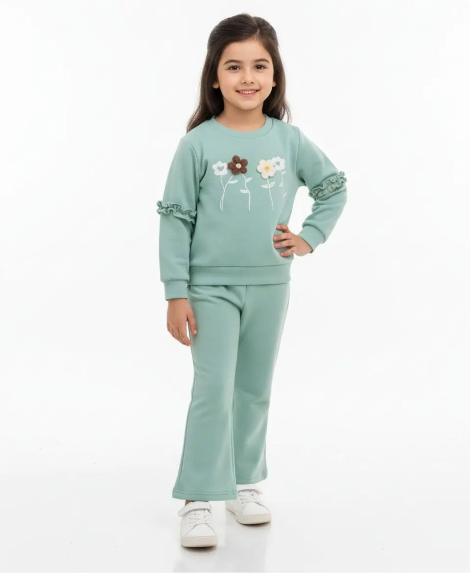 Young girl wearing a light green outfit with floral designs on a white background