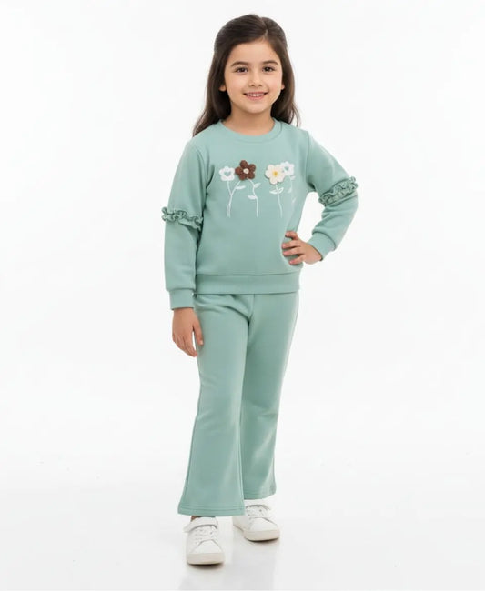 Young girl wearing a light green outfit with floral designs on a white background