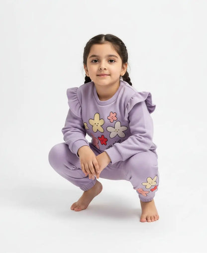 Young girl wearing a purple outfit with floral designs on a white background