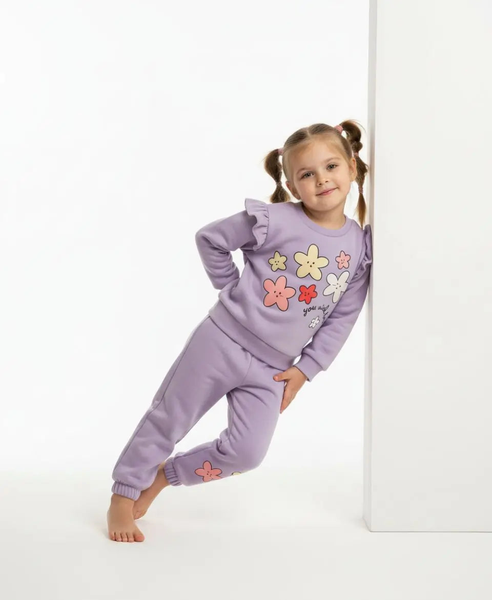 Child wearing a purple outfit with floral designs on a white background